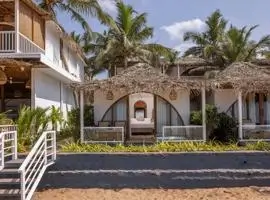 A tropical beach house with a thatched roof and palm trees, offering a serene escape by the sea.