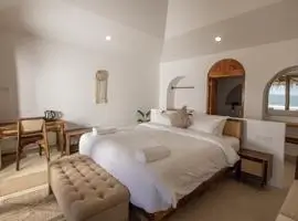 Bedroom with bed and ocean view, featuring calming blue hues and natural light pouring in through large windows.