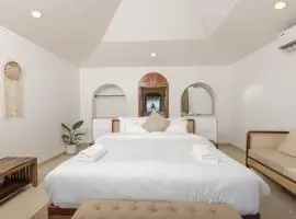 A cozy white bed in a room with a high ceiling, inviting you to relax and unwind.