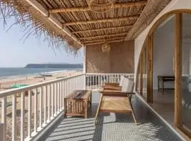 A wooden balcony railing overlooking the beach with a beautiful view of the ocean.