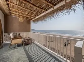 A cozy beach house with a wooden porch overlooking the vast ocean.